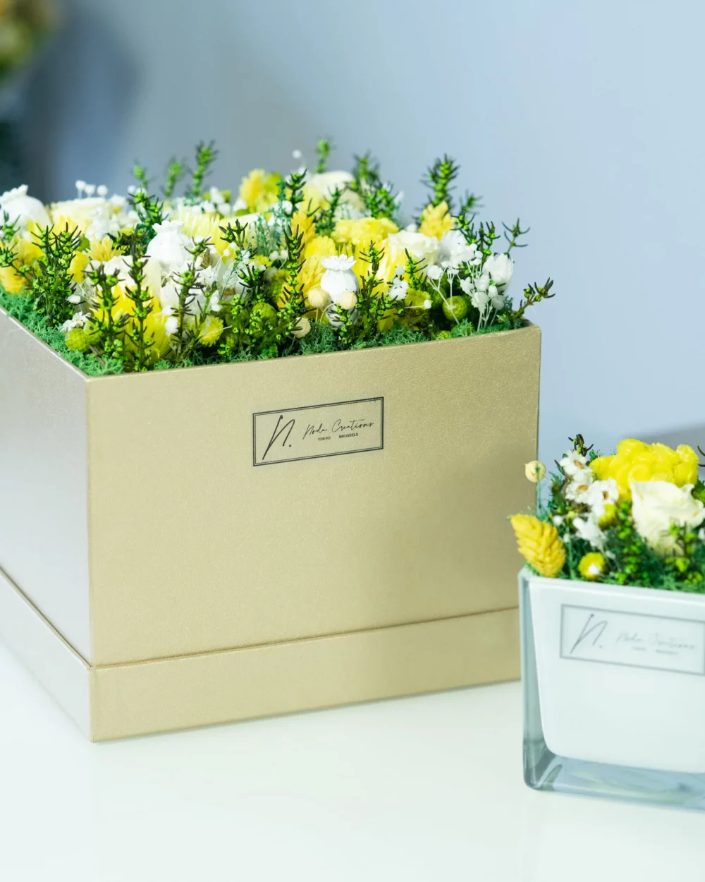 white and yellow preserved flowers in a brown box. a mini sunny garden
